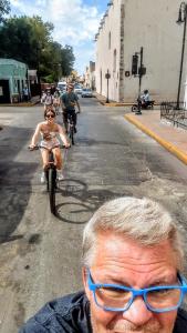 a man wearing blue glasses standing in the street with people riding bikes at The Blue Eco Lodge in Valladolid