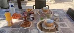 a table topped with cups and plates of breakfast food at Les murmures du jardin in Pégomas