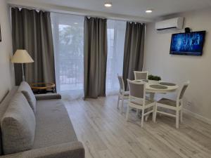 a living room with a couch and a table and chairs at Apartamentai įsikūrę Šventojoje in Palanga