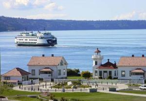 a cruise ship in the water next to a lighthouse at Soundview Ferry Cottage in Mukilteo