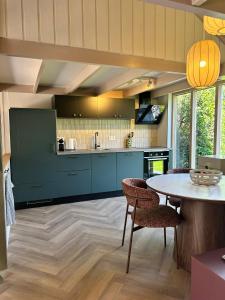 a kitchen with blue cabinets and a table and chairs at De Strandjutter in Warmenhuizen