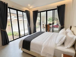 a bedroom with a large bed and large windows at The Arya Srithanu in Ko Kong Nui