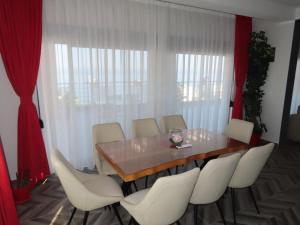 a dining room with a wooden table and white chairs at Mir i More in Dobra Voda