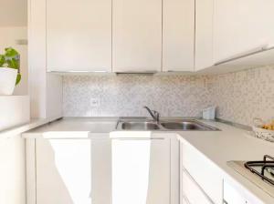 a kitchen with white cabinets and a sink at Il Girasole - Appartaments in Domus de Maria +7 photos