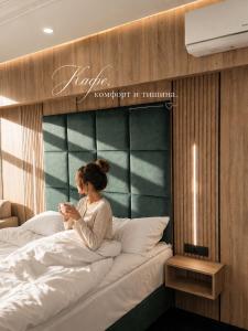 a woman sitting on top of a bed at Hotel Paradise in Ognyanovo