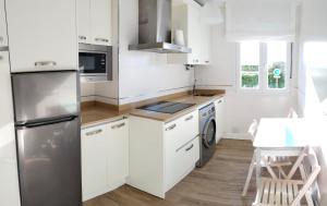 a kitchen with white cabinets and a stainless steel refrigerator at Casa Roca Blanca Suances in Suances
