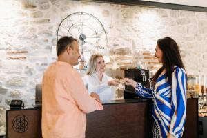 a man and two women standing at a counter at Murum Heritage Hotel in Split