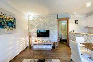 a living room with a tv and a brick wall at Apartment Mistral in Molunat