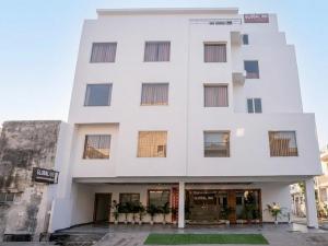 a white building with plants in front of it at Hotel Global Inn Gold in Lucknow