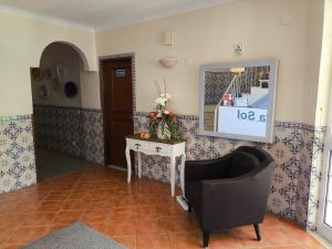 a living room with a chair and a mirror at Aurora Sol in Luz