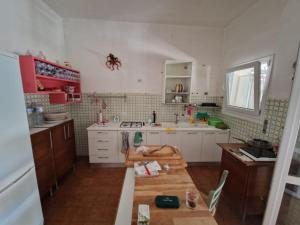 a kitchen with white cabinets and a wooden table at Villino Irmgard in Butera +4 photos