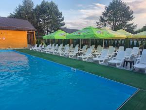 a swimming pool with white chairs and umbrellas at Oasis in Edineţ