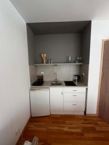 a small kitchen with white cabinets and a sink at Domek Augustów Monika in Augustów +5 photos