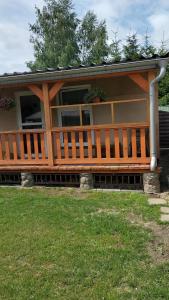 a house with a large wooden porch on the grass at Domek Augustów Monika in Augustów