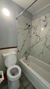 a bathroom with a white toilet and a bath tub at Ada Inn & Suites in Ada +13 photos