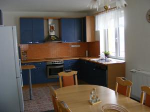 a kitchen with blue cabinets and a wooden table at Holiday Home U Fišerů in Kašperské Hory