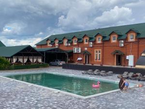 two children playing in a swimming pool in front of a building at Готель Зелений Клин in Gubnik