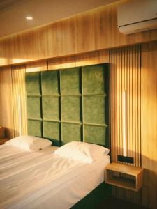 a bedroom with a bed with a green headboard at Hotel Paradise in Ognyanovo