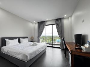 a bedroom with a bed and a desk and a window at De Zee Hotel in Koh Kong