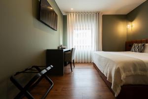 a bedroom with a bed and a desk and a window at Santo Thyrso Hotel in Santo Tirso