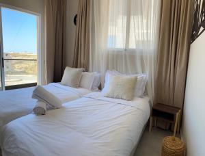 two beds in a hotel room with a window at Imsouane Harmony in Imsouane