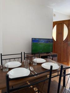 a dining room table with plates and a television at gvero apartments in Prilep +3 photos