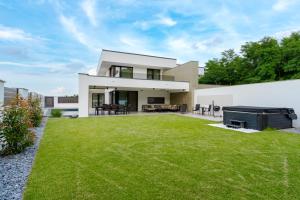 a large backyard with a lawn in front of a house at Villa Glam Wellness & Spa Retreat in Mogyoród