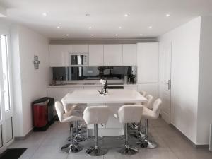 a kitchen with white cabinets and a white table and chairs at La maison spacieuse et confortable in Deauville