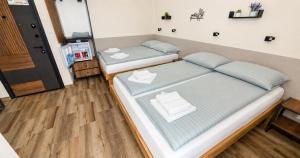 two beds in a small room with wooden floors at Park and Fly Belgrade Airport Apartments in Surčin