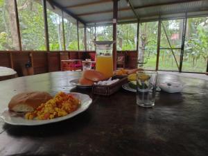 a table with plates of food and a glass of orange juice at Musas Garden Lodge Tambopata in Puerto Maldonado +29 photos