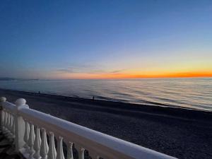 a sunset over the ocean with a white fence at Mari House in Buknari