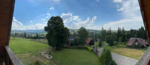 a view of a green field with a tree and houses at Villa Szarotka in Dzianisz