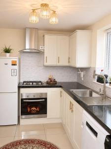 a kitchen with white cabinets and a fire in the oven at London Heathrow Accommodation in Hillingdon