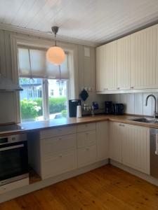 a kitchen with white cabinets and a large window at Mølleråsen Apartment in Sandefjord