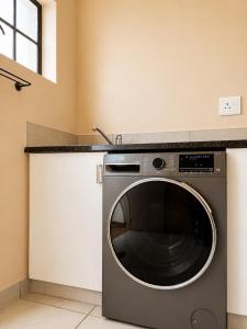 a washing machine in a kitchen with a counter at Oceanfront Escape Beach House in Strand