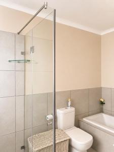 a bathroom with a toilet and a glass shower door at Oceanfront Escape Beach House in Strand +9 photos