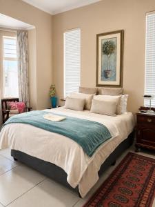 a bedroom with a large bed with a picture on the wall at Oceanfront Escape Beach House in Strand