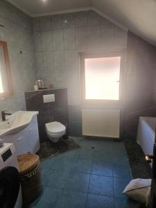 a bathroom with a sink and a toilet and a window at Lucija in Tenja