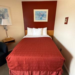 a hotel room with a bed with a red bedspread at Trunk Road Motel in Sault Ste. Marie