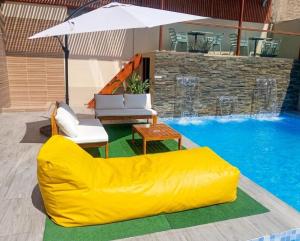 a yellow couch sitting next to a swimming pool at Regency Plaza Hotel in Pisco