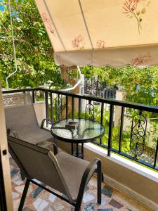 a balcony with a glass table and chairs and a window at Blossom Apartment Kos in Ampavris