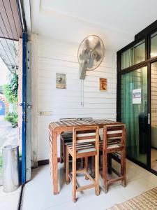 ein Zimmer mit Tisch, Stühlen und einem Ventilator in der Unterkunft La Locanda in Bangkok