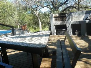 a table and chairs on a deck with trees at Tjhora Sunset Cottage in Cambridge