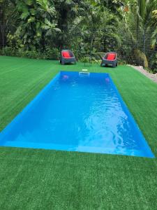 a swimming pool on grass with two stools at Ti cocon nature in Sainte-Anne