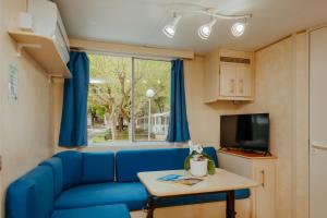 a living room with a blue couch and a table at Green Garden Village con piscina, spiaggia riservata e parcheggio in Sirolo