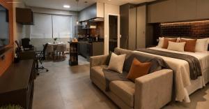a bedroom with a bed and a couch and a kitchen at Excelente Apto Moderno e espaçoso no Cittyplex Osasco in Osasco