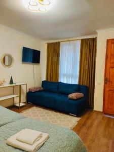 a living room with a blue couch in front of a window at Gallery in Tsʼageri