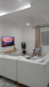 a living room with a white couch and a flat screen tv at Imani staycation Penthouse Diani in Diani Beach