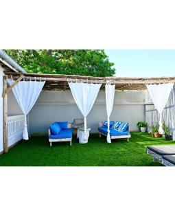 a patio with two blue chairs and white curtains at Imani staycation Penthouse Diani in Diani Beach