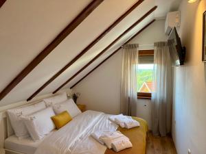 a bedroom with a bed with white sheets and a window at Deer Hill in Orahovica